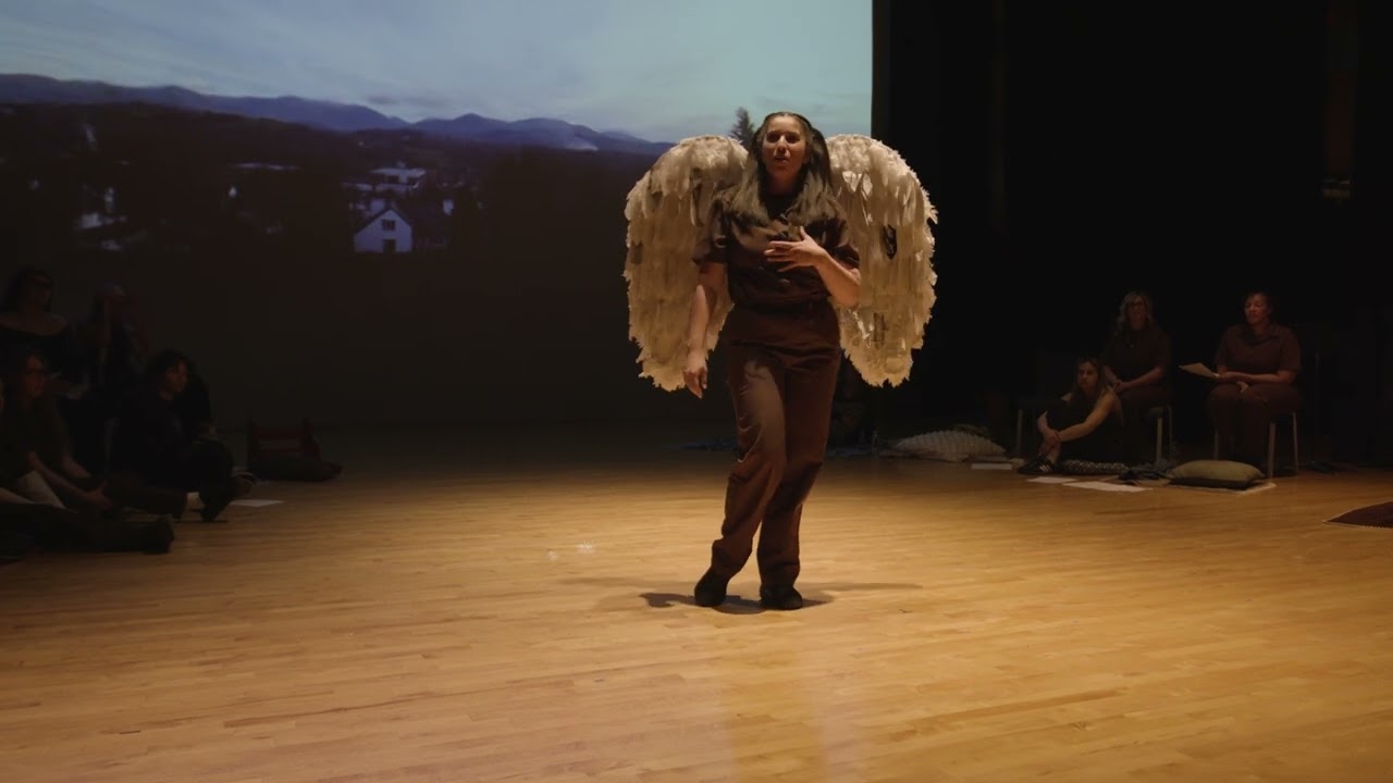 Woman with wings on standing on stage talking